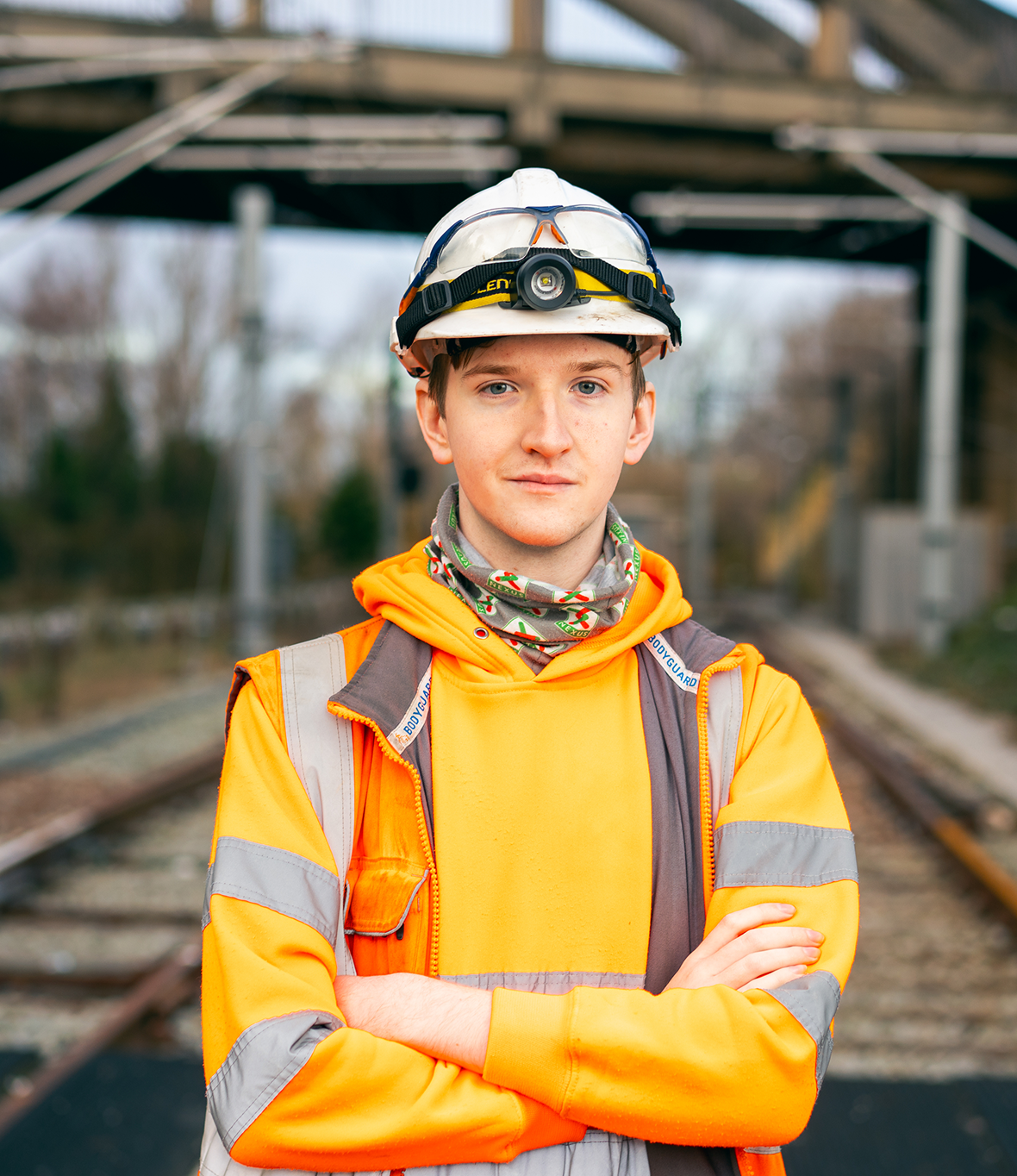 A man wearing full high vis clothing standing on a train track