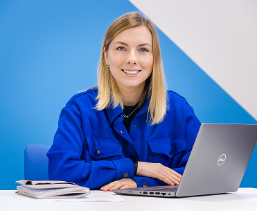 Blonde female sitting at a table with a laptop in front of her