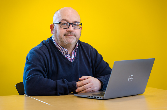 A male Nexus employee sat in front of a laptop