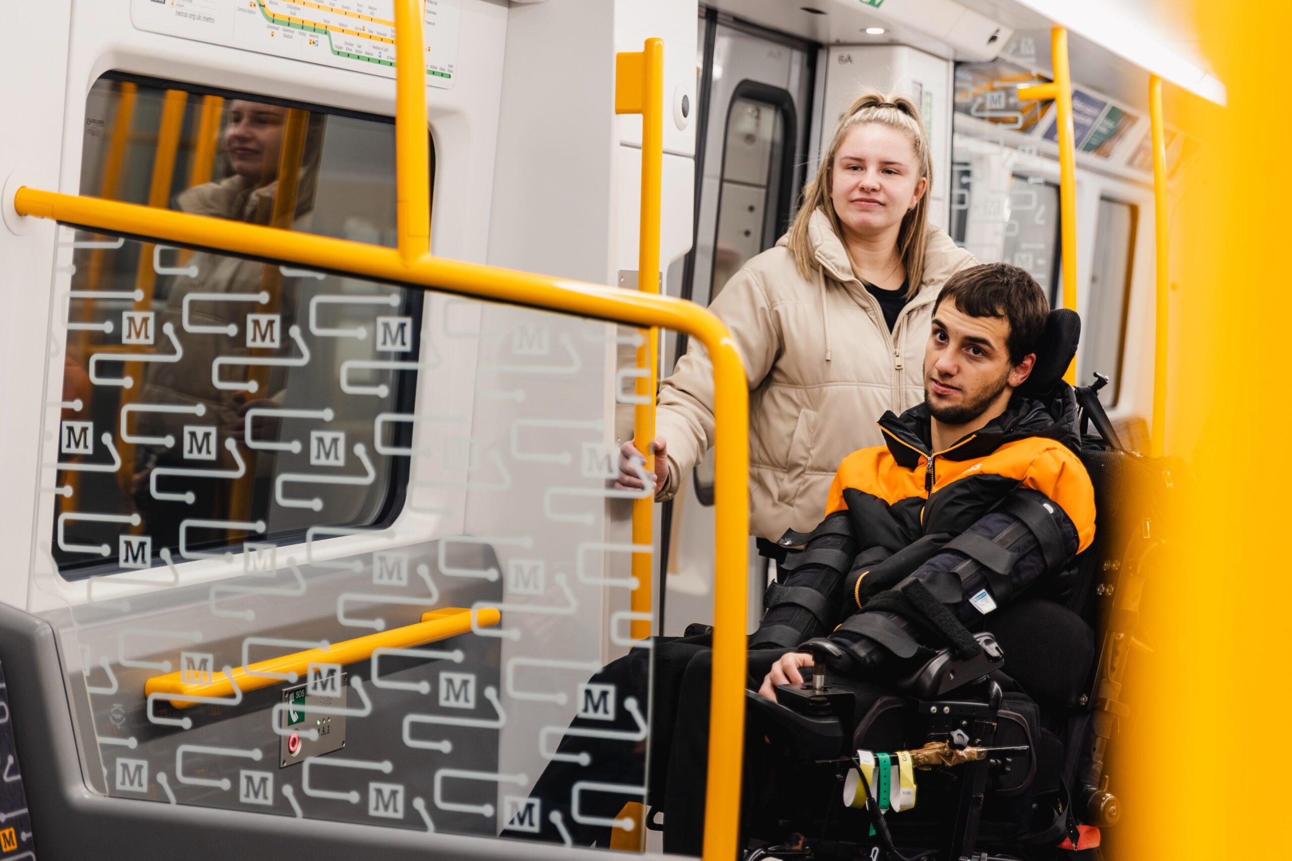 A man in a wheelchair and a woman standing behind him on a Metro train