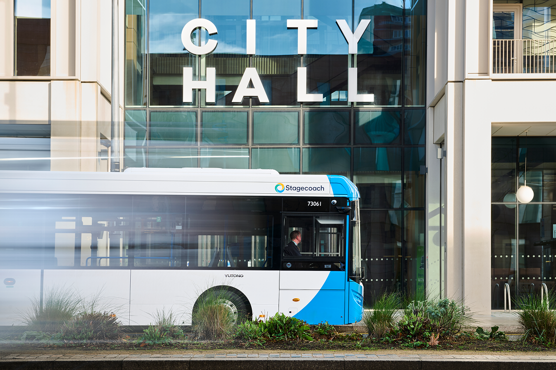 A Stagecoach bus travelling outside a building with City Hall written on the outside