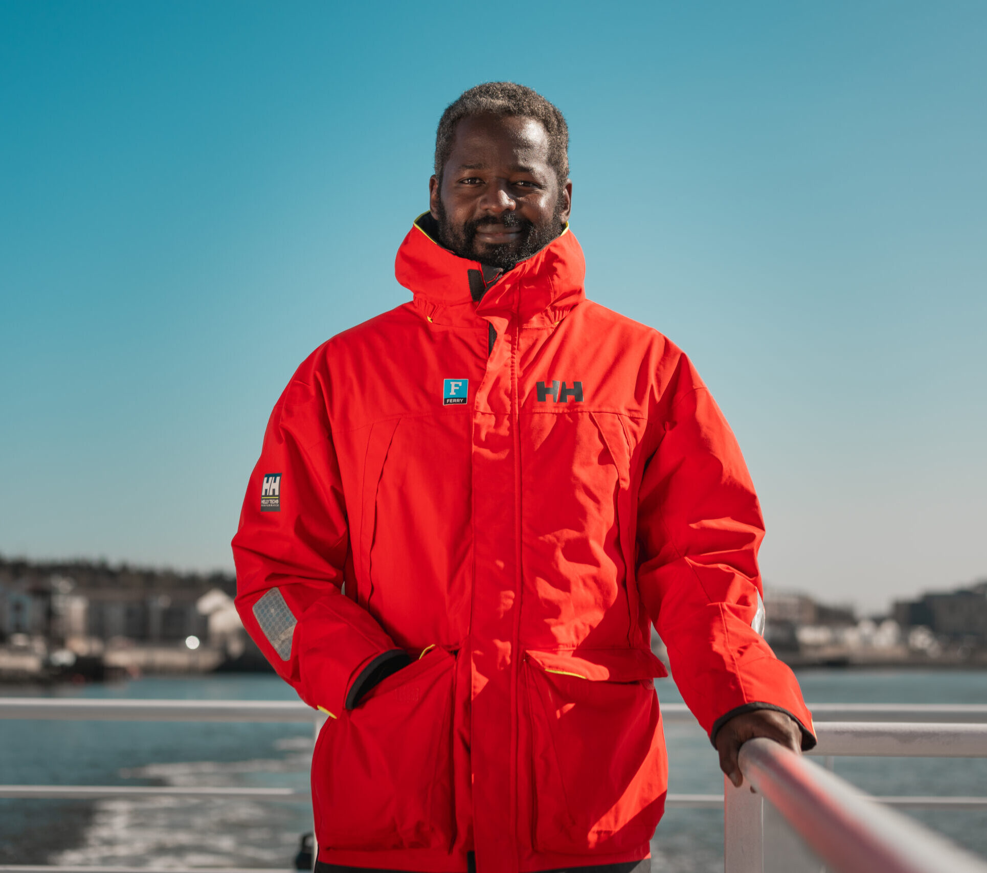 A man on the deck of the ferry wearing a red coat
