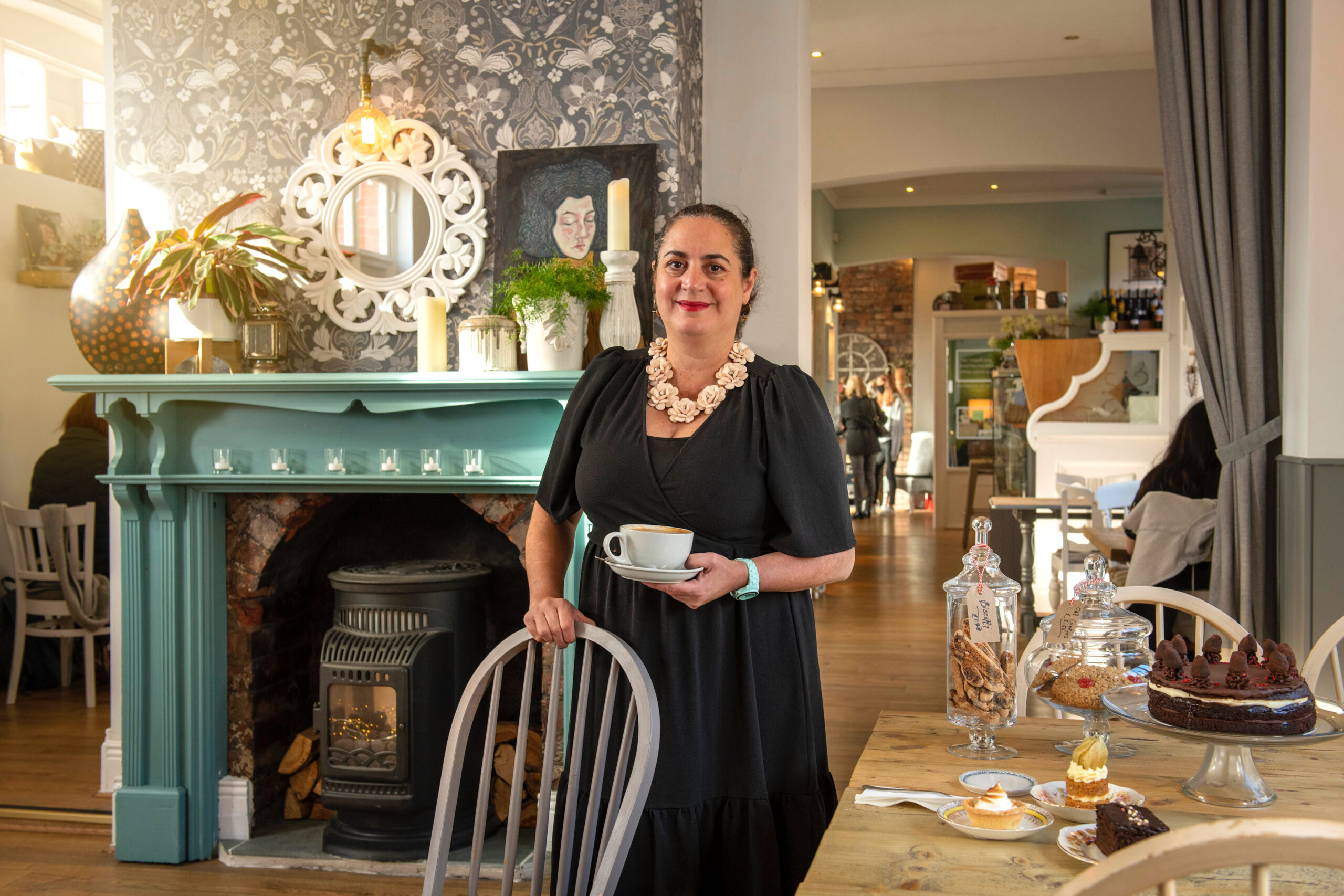 AN image of a lady in a black dress standing in a cafe