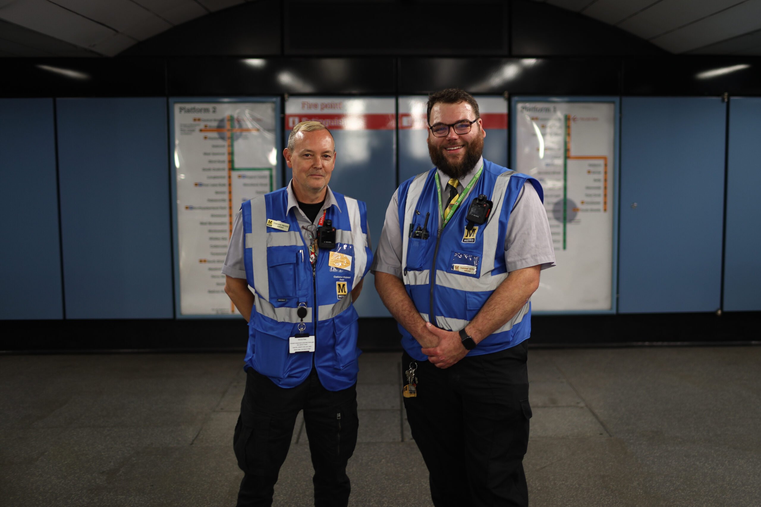 Two men in blue high vis vest in a Metro station