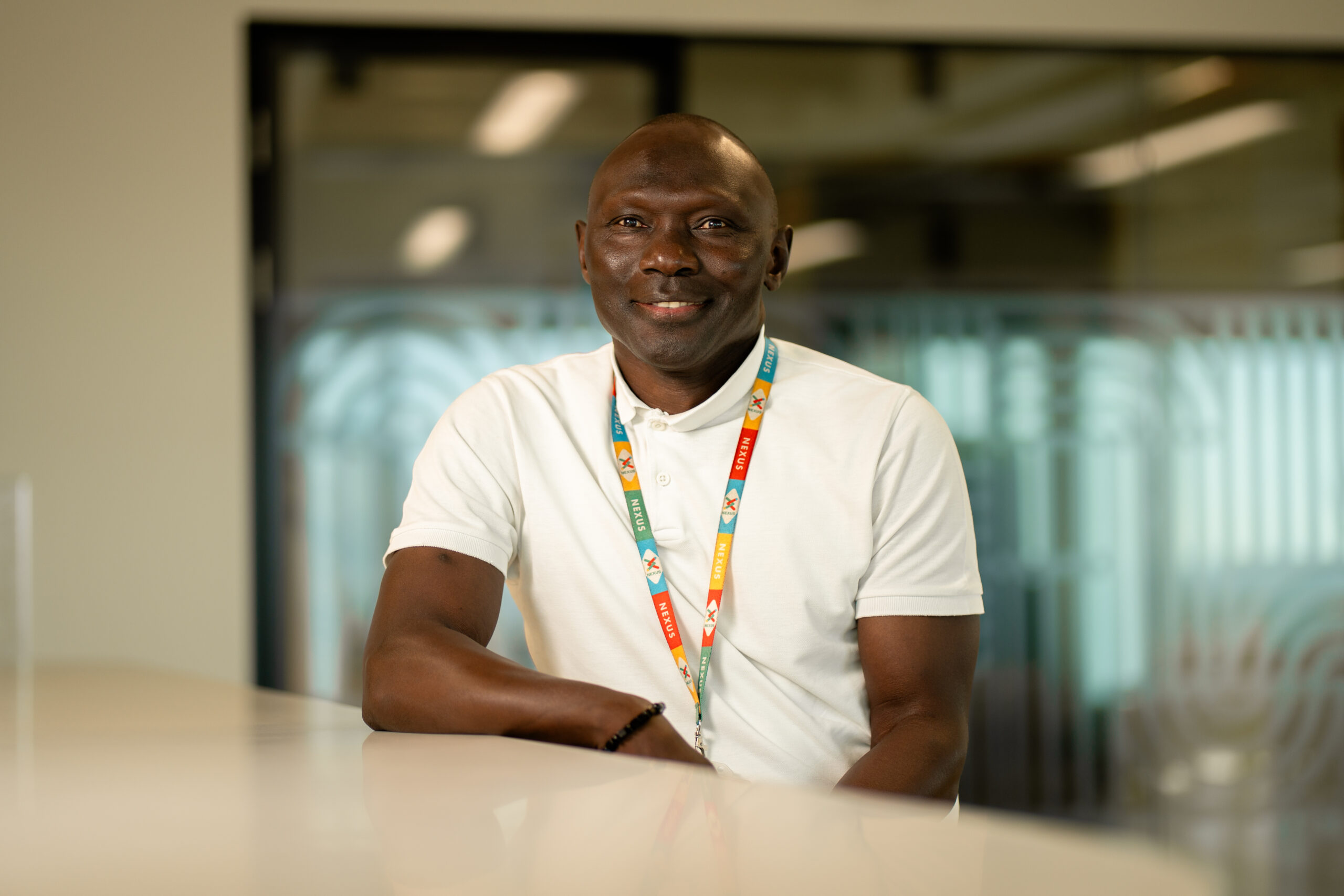 A man in a white t shirt sitting at a white desk